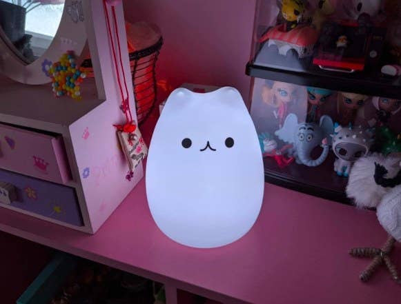 white glowing kitty night light sitting on a desk