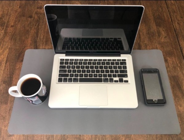 reviewer&#x27;s grey desk mat with computer mug and phone on it