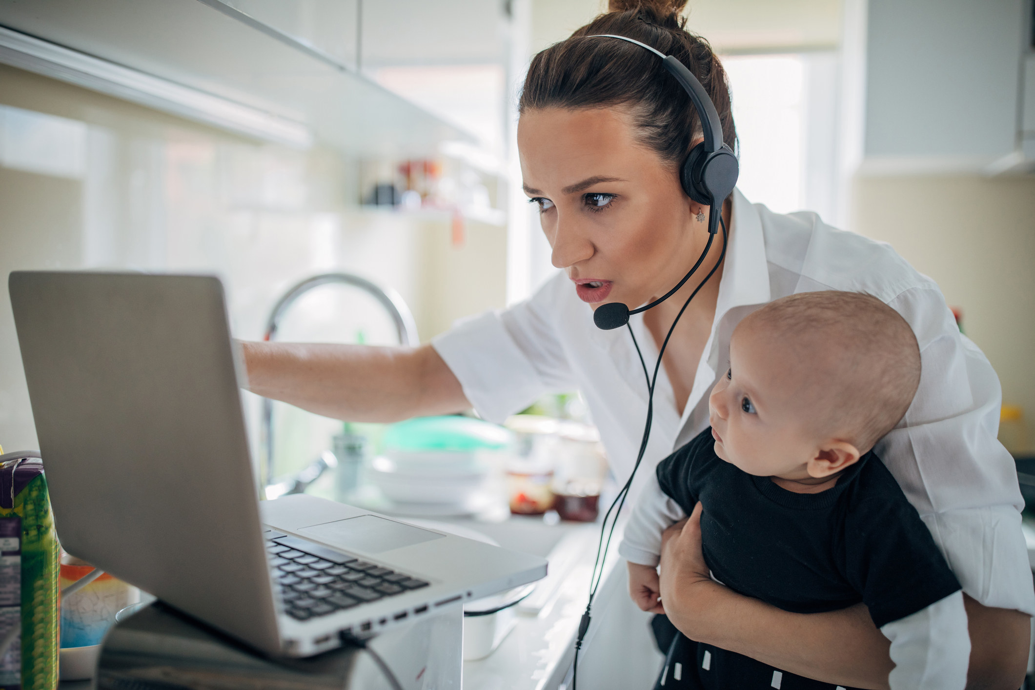  Mom holding her baby while working on her laptop