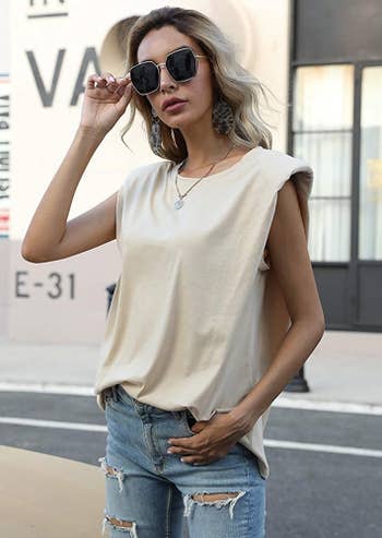 model in white sleeveless shoulder pad top and jeans