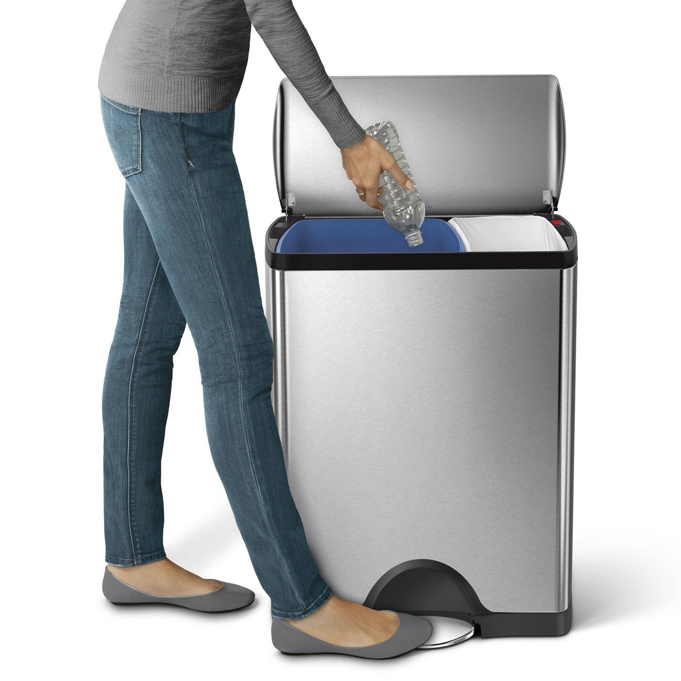 woman stepping on the step of a stainless steel trashcan with two compartments inside