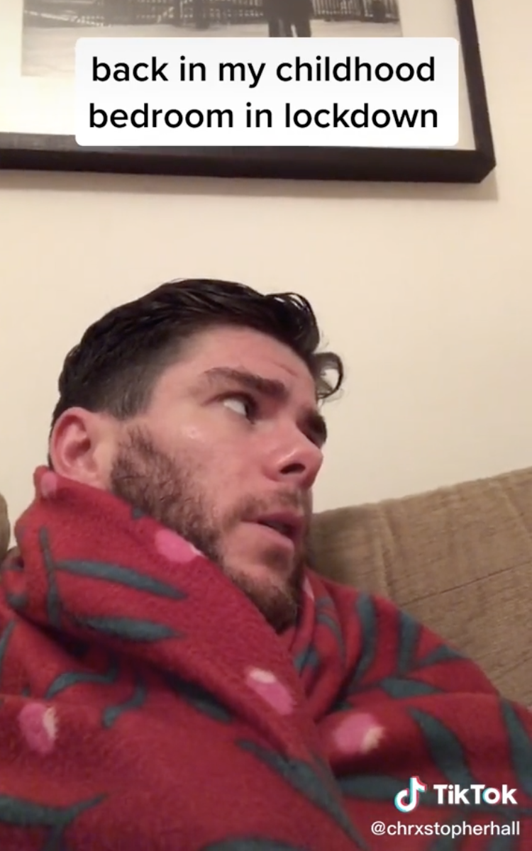 Man sitting on the couch wrapped in a blanket and talking