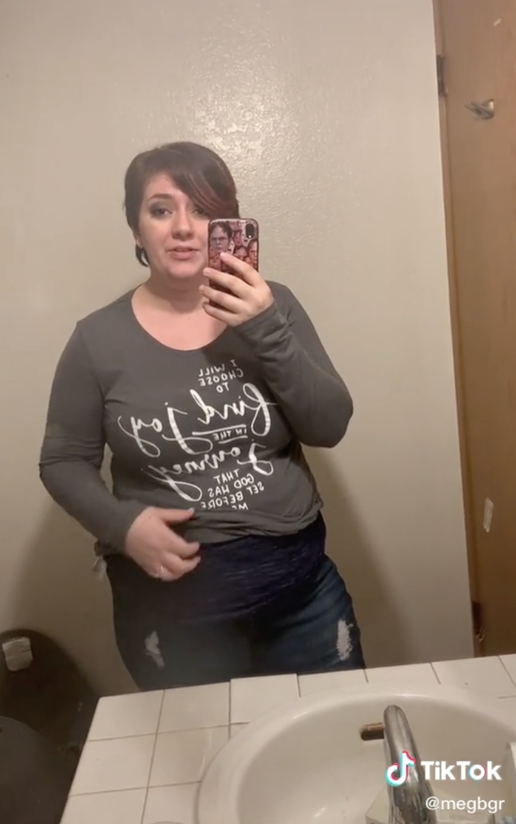 Woman showing the tank beneath her long-sleeve in the bathroom