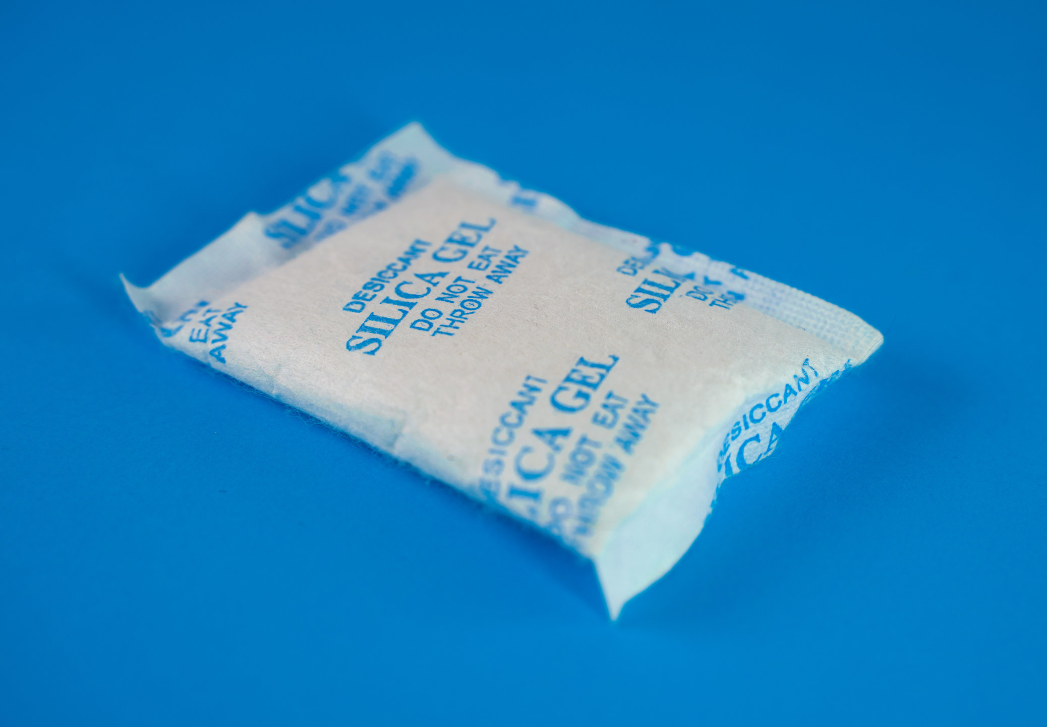 A silica gel packet on a blue table