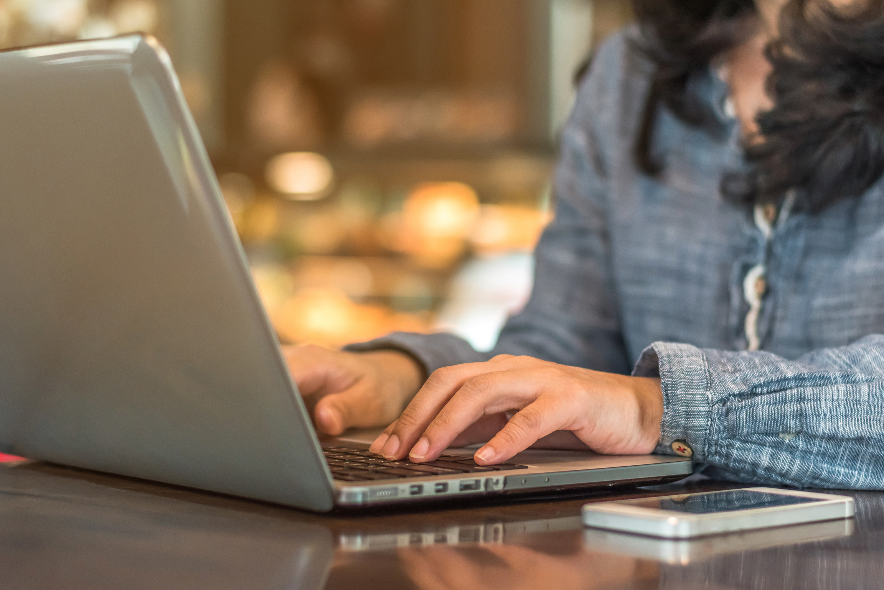 Close-up of a woman typing on her laptop