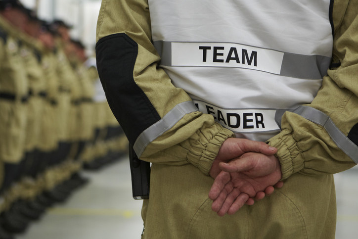 A team leader in a suit, crossing hands behind their back