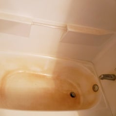 a reviewer photo of a tub with dark water stains 