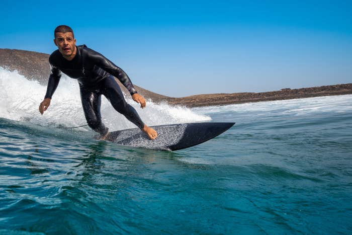 Surfer in wet suit riding surfboard in ocean