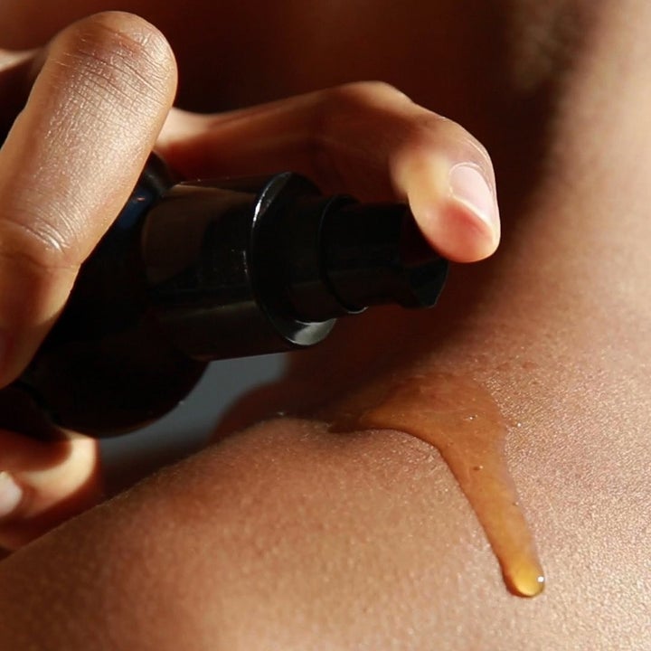 Someone squirting some massage oil onto their shoulder