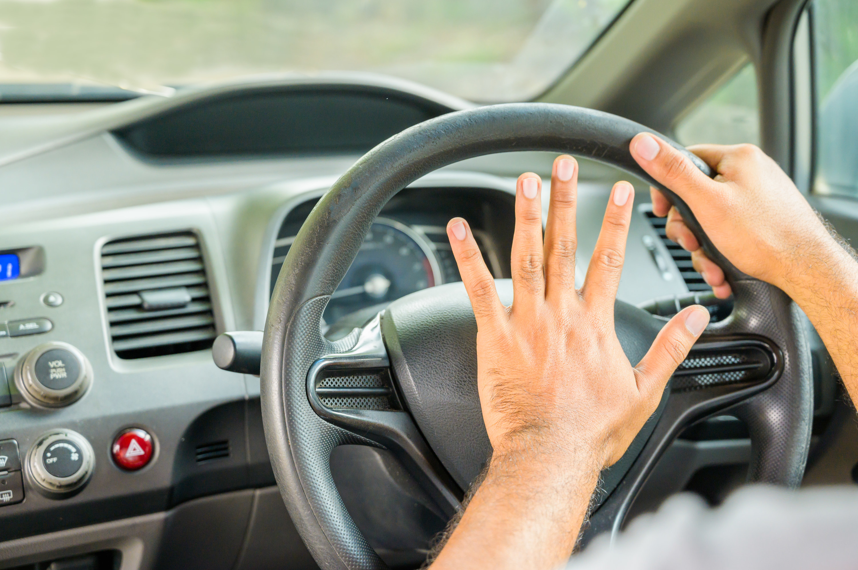 Man grabbing steering wheel with left hand pressing his horn