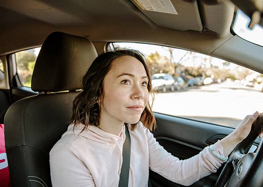 Woman sits in the driver seat while looking ahead. 