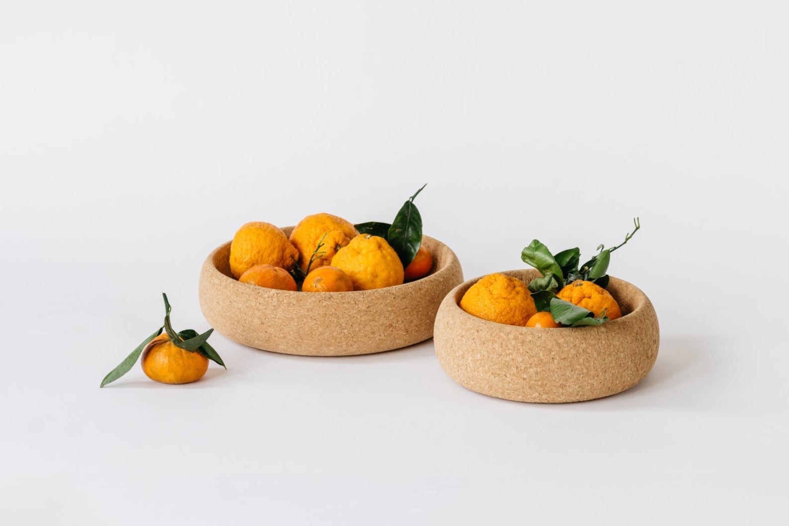two large round tan bowls with oranges in each one
