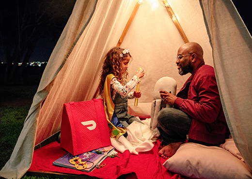 A man spends time with his daughter in a homemade fort.  