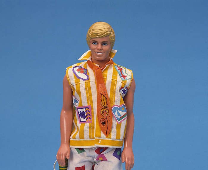 Ken doll from the 80s with blonde hair wearing a wacky 80s sleeves less shirt and fish tie