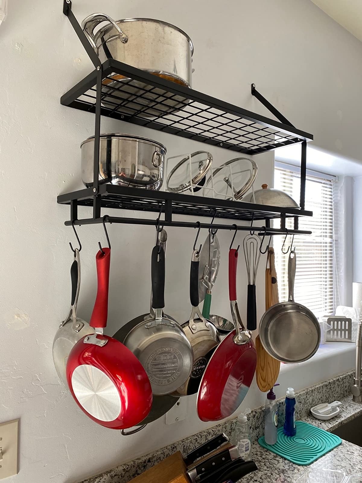 reviewer image of the KES 30-Inch Hanging Kitchen Rack mounted on a wall with several pots and pans hanging from its bottom hooks