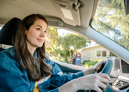 A woman drives through a suburb. 