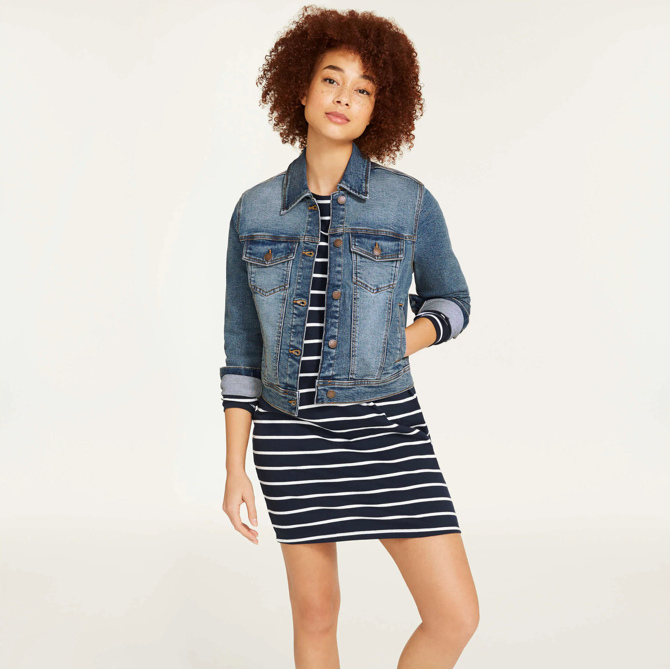 A person wearing a jean jacket over a dress