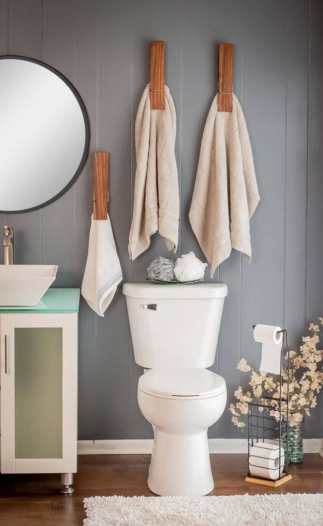 giant clothespin towel holders clasped onto large towels above a toilet