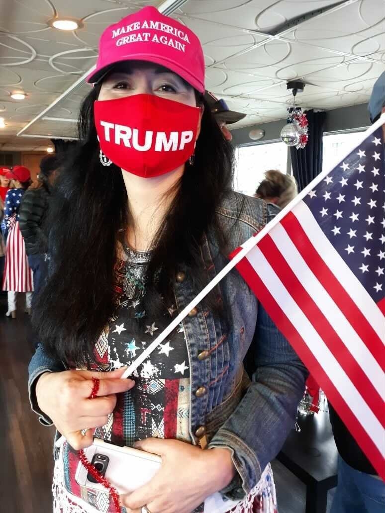 She wears a Trump face mask and holds an American flag