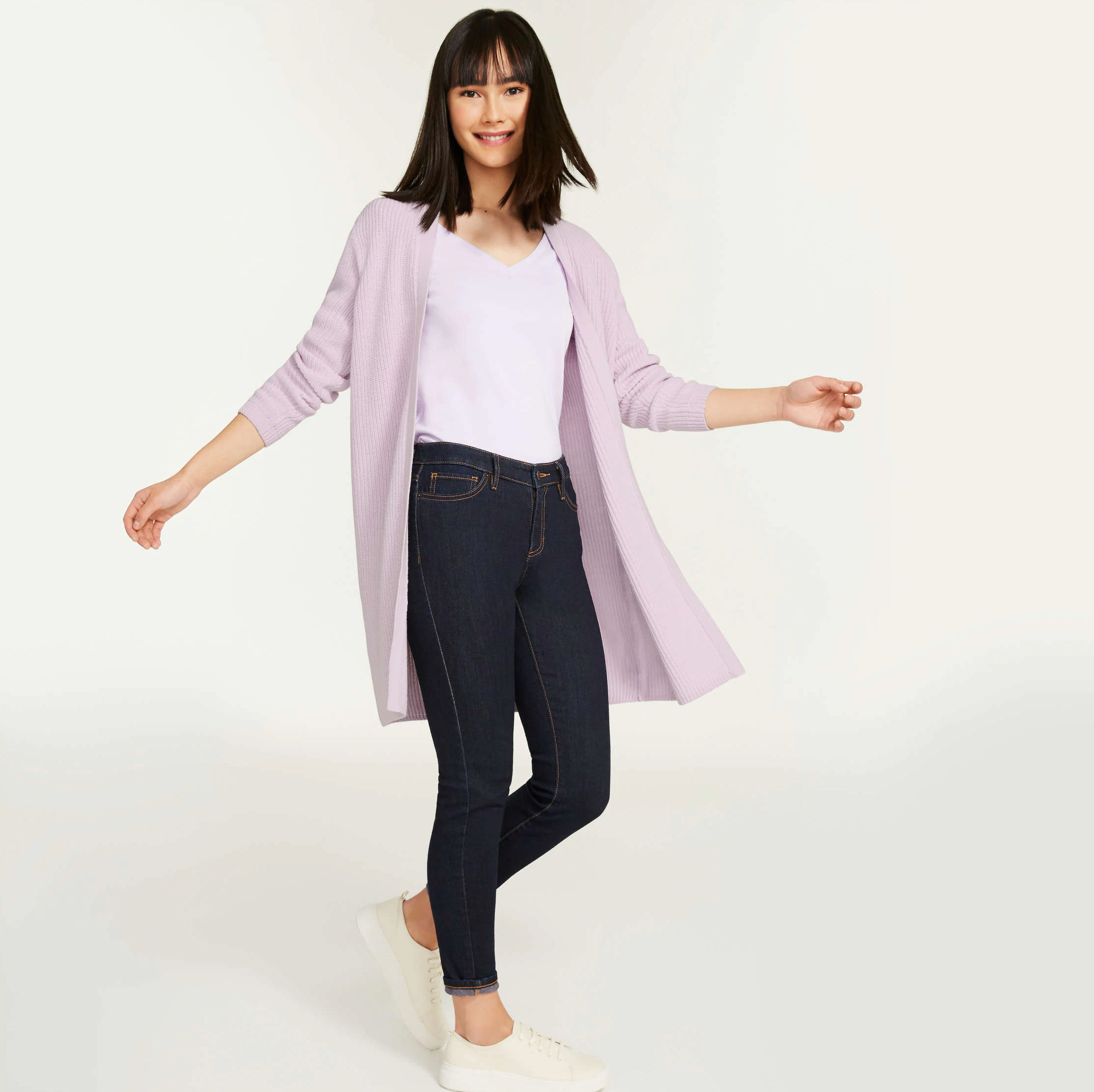 A person wearing a long cardigan over a T-shirt and jeans