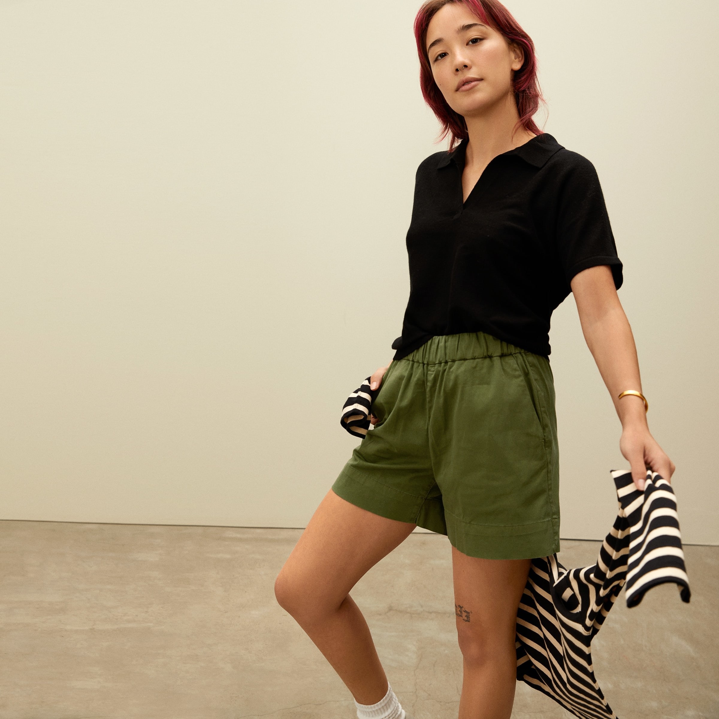 a thin model wears the fern colored easy short  with a loose black polo
