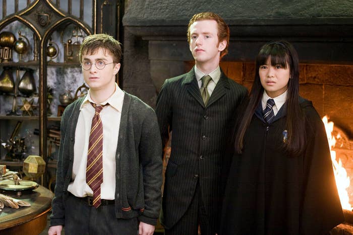 Daniel Radcliffe, Chris Rankin, and Katie Leung standing in front of a roaring fireplace in Harry Potter and the Order of the Phoenix