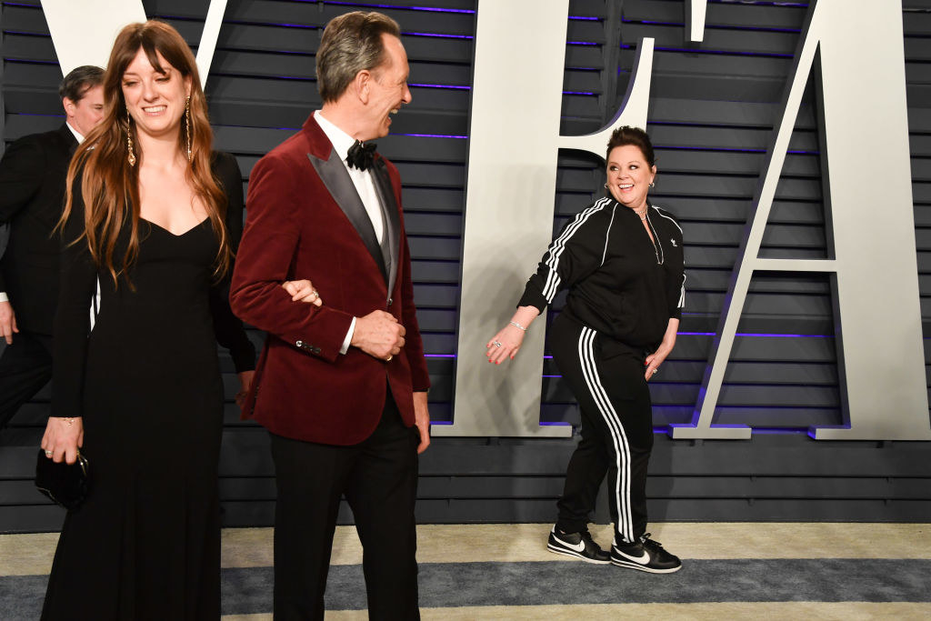 Melissa McCarthy looks behind her as she walks the 2019 Vanity Fair Oscar Party red carpet as other celebrities look on