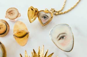 Several tiny gold necklaces, rings, and pendants with painted scenes and eyes 