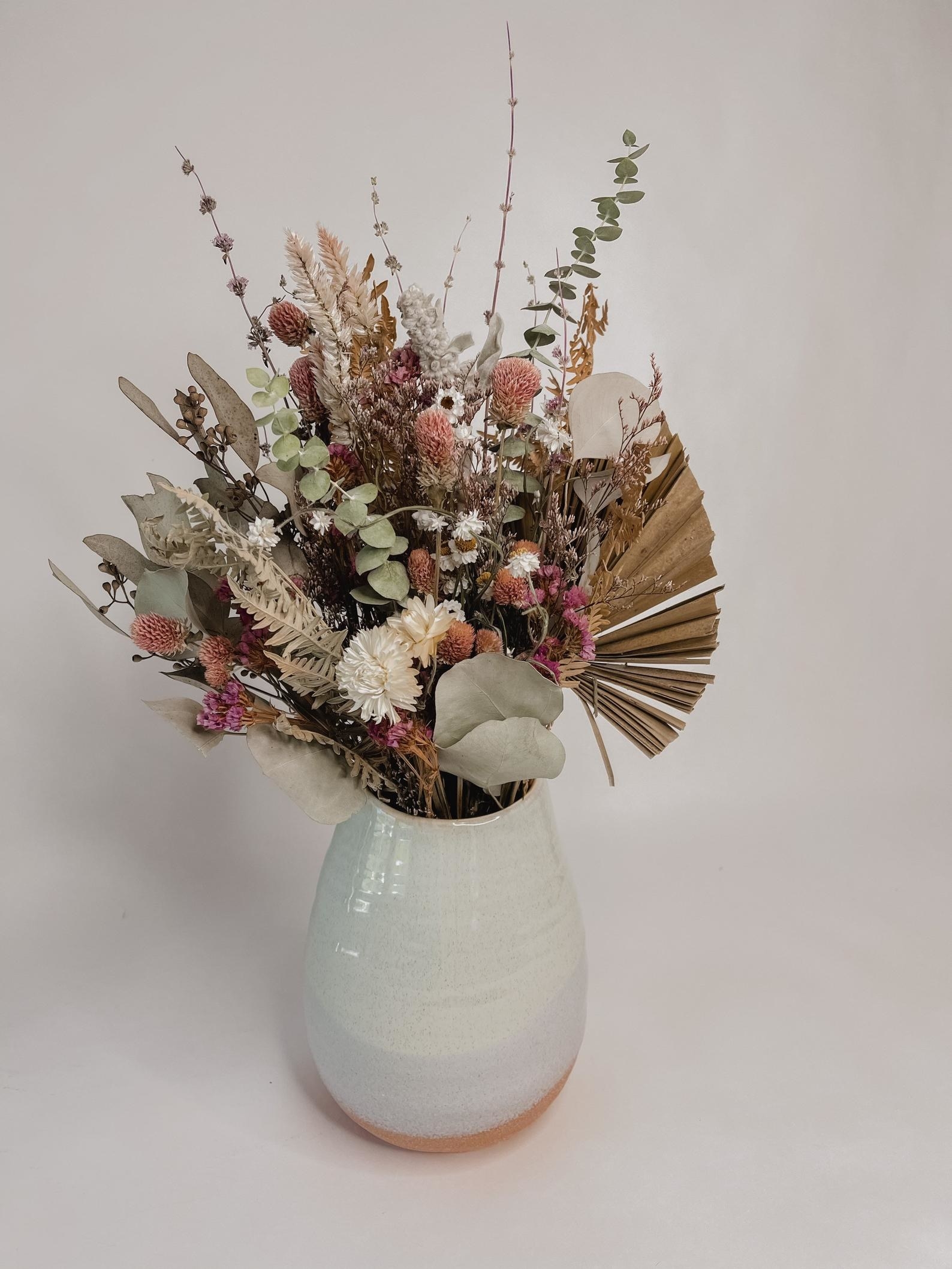 bouquet of different dried flowers and greenery in a vase
