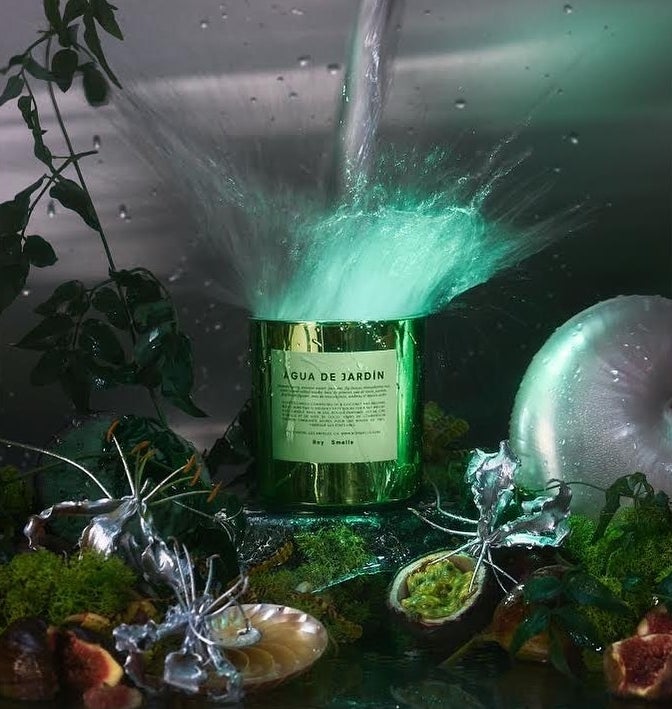 The scented candle surrounded by Botticelli-esque plant life and glittering metallic sculptures