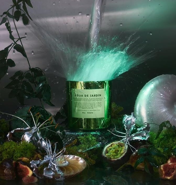 The scented candle surrounded by Botticelli-esque plant life and glittering metallic sculptures