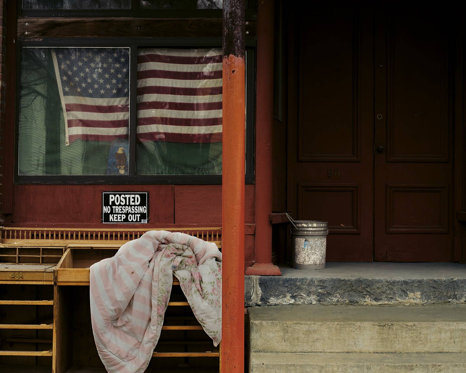 An American flag in the window of a store with a sign that says "no trespassing"