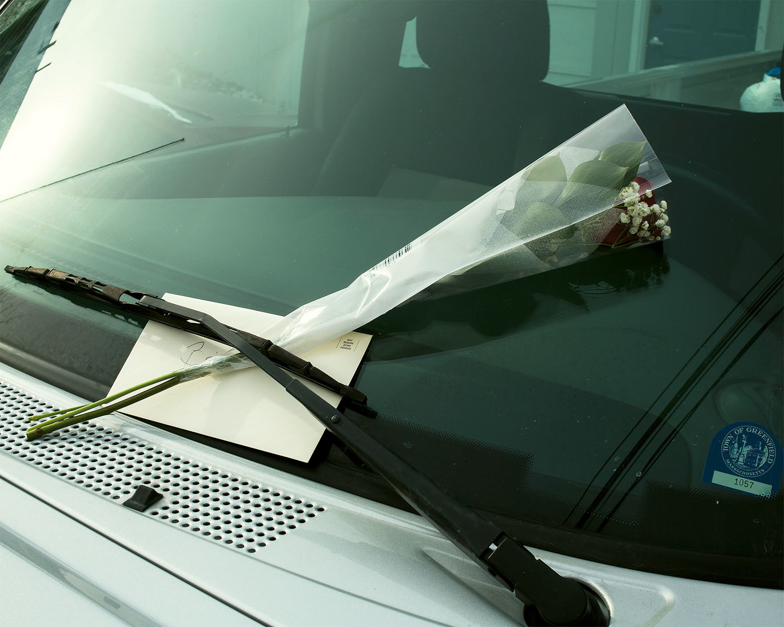 A flower and a card on the windshield of a car