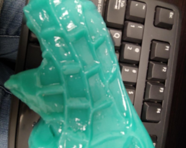 Person cleaning their keyboard with the slime-like cleaner