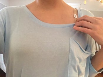 A reviewer photo of someone wearing a thing light blue T-shirt with no visible bra showing 