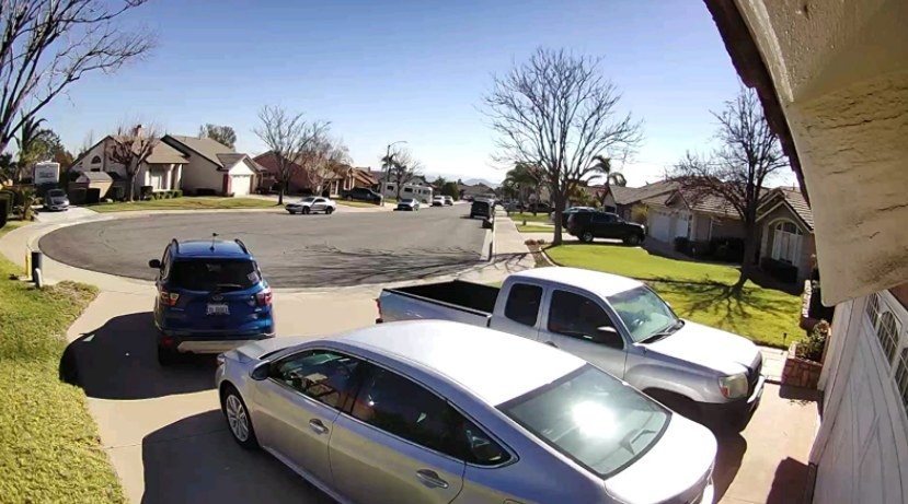 A fisheye lense on a driveway with three cars on a culdesac 