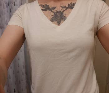 a reviewer selfie of someone showing that the bra does not show under the shite t-shirt they're wearing 