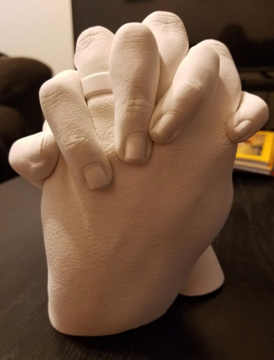 A white plaster mold of two clasping hands. 