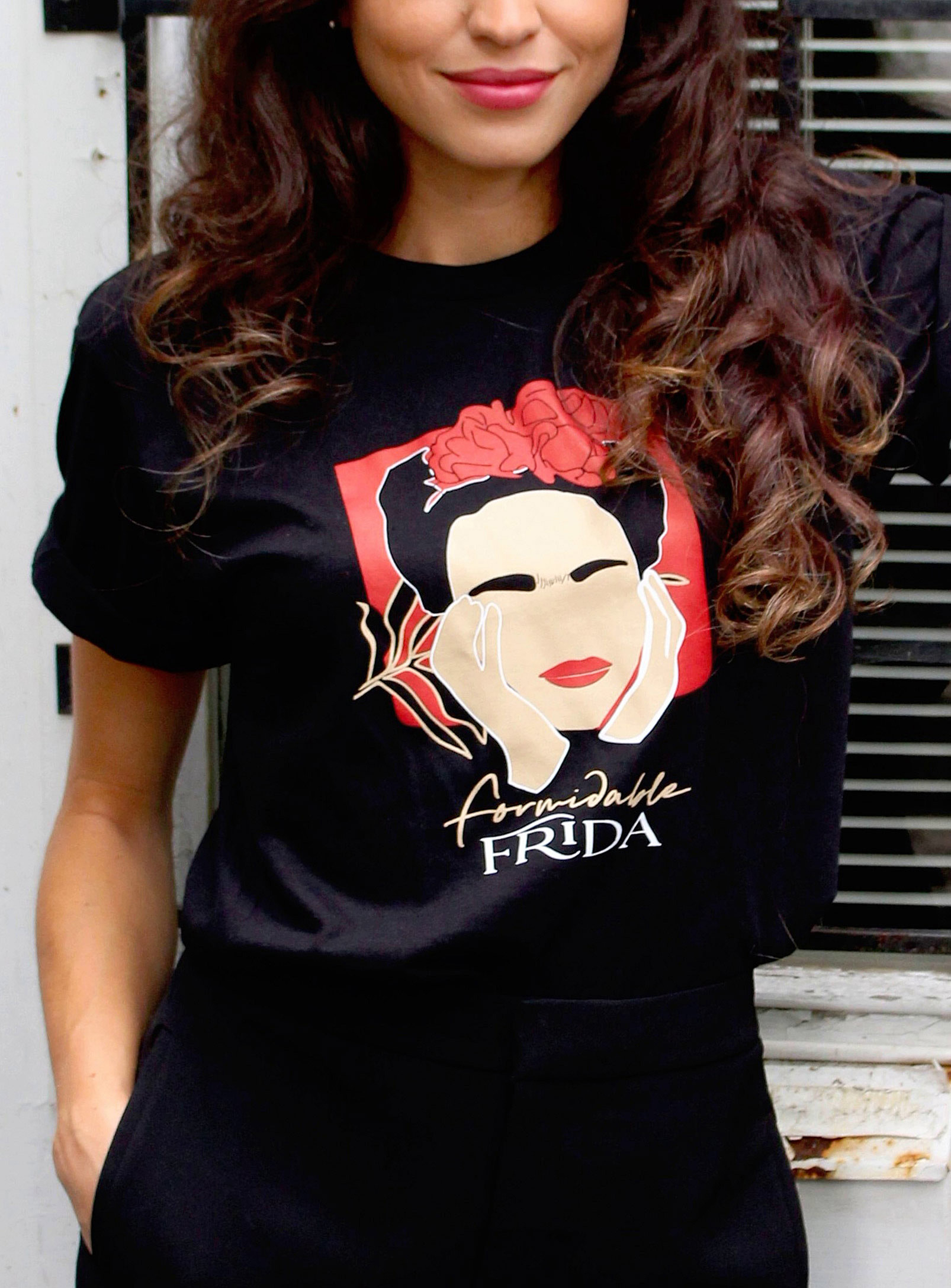 A person wearing a graphic T-shirt with an illustration of Frida Kahlo
