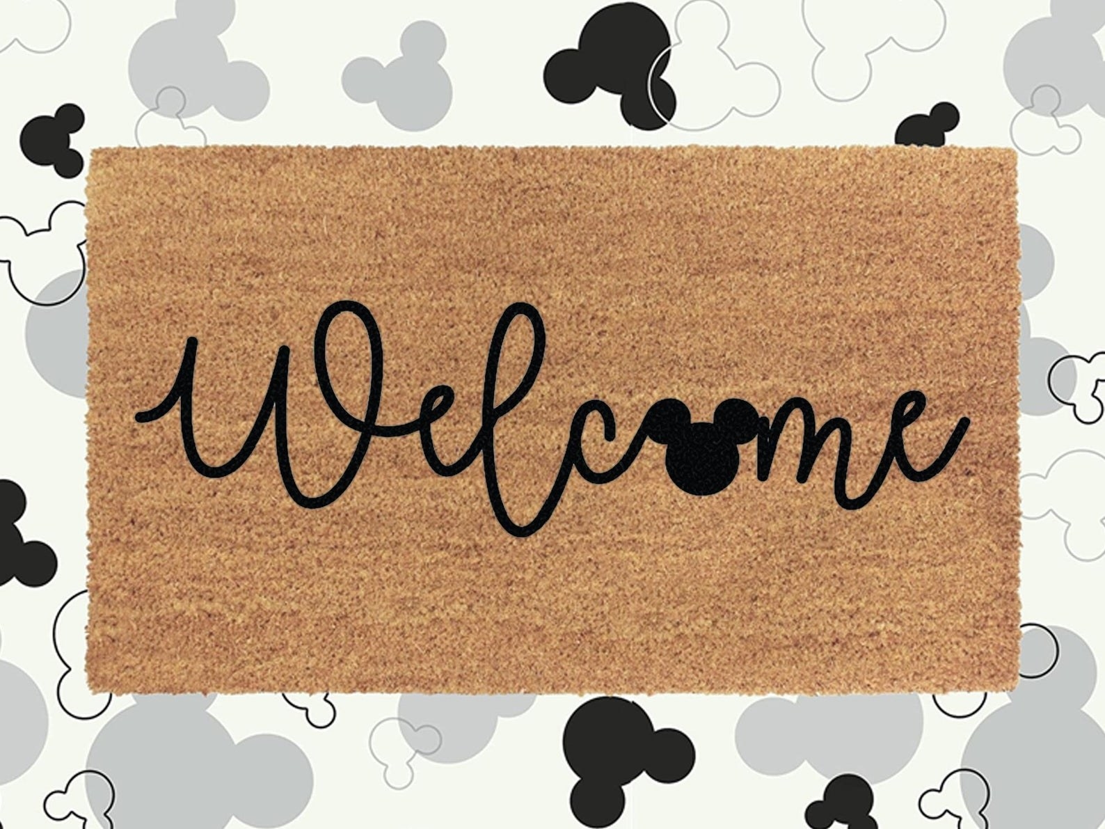 Brown welcome mat that says &quot;Welcome&quot; in black, with a Mickey shape as the &quot;o&quot; 