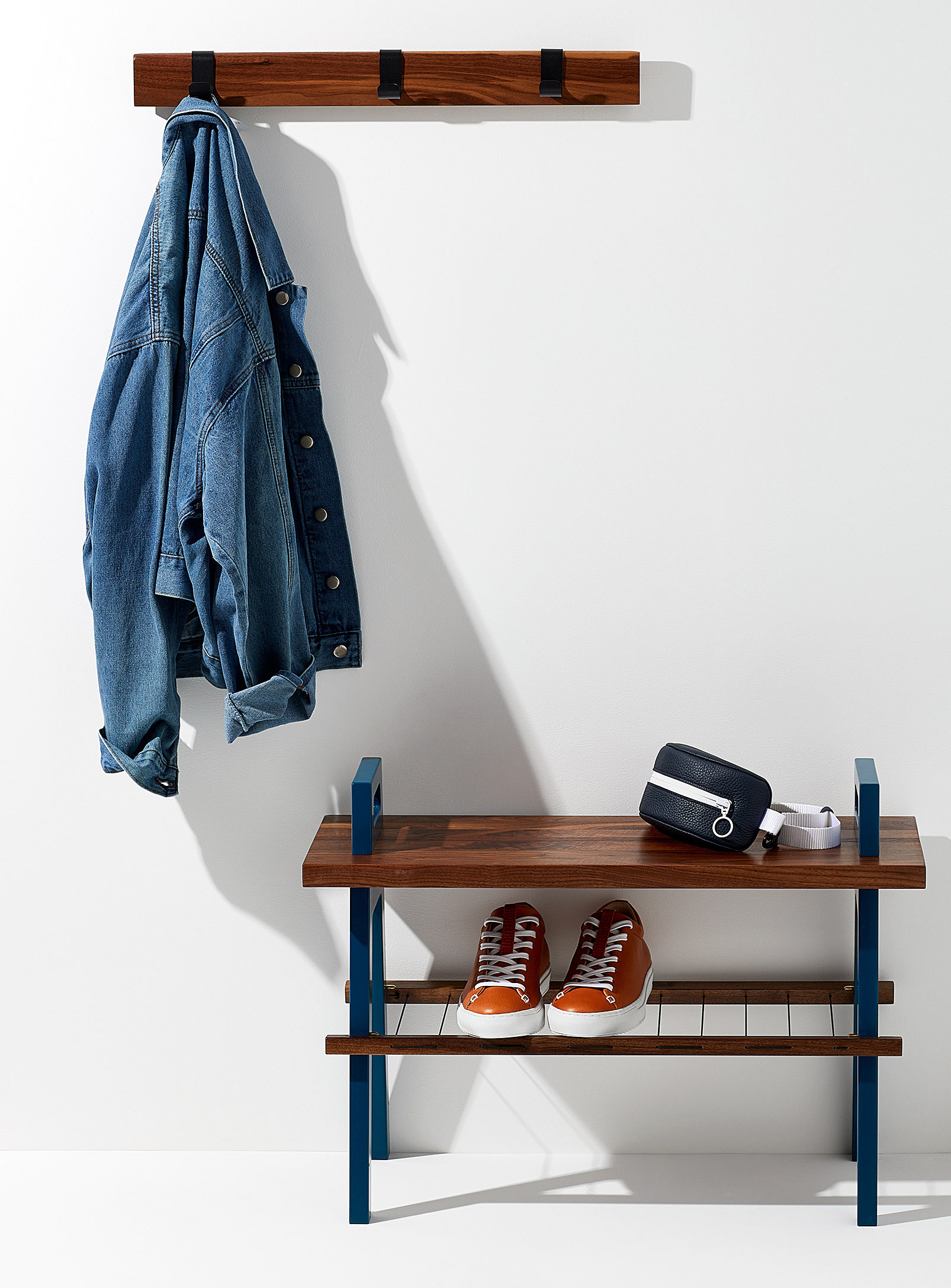 A wooden bench underneath a coat rack