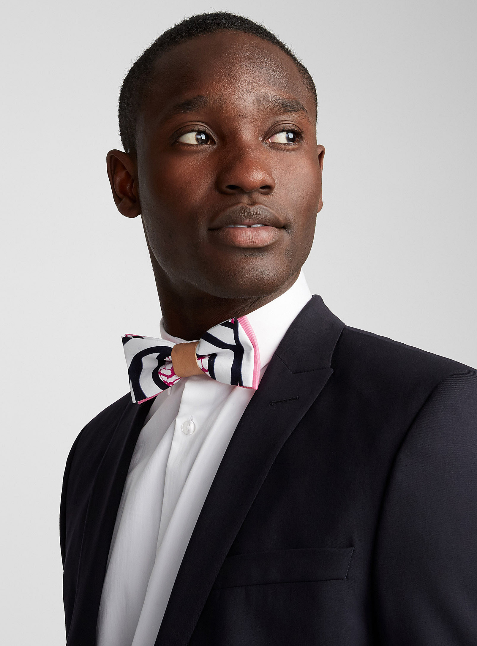 A person wearing a bow tie with their button up shirt and blazer