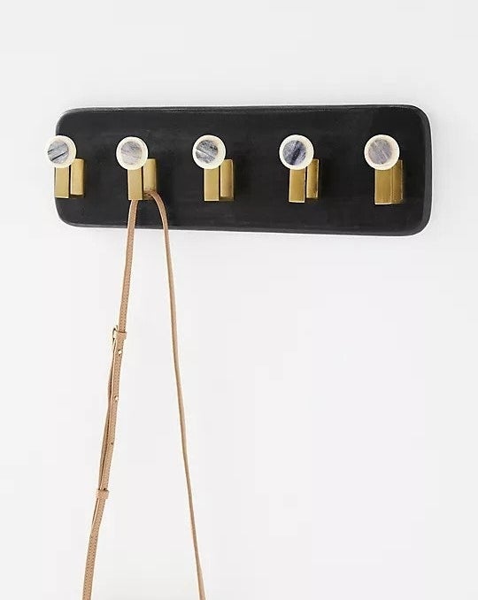 Rectangular mounted coat rack with rounded edges and five gold hooks with marble details 