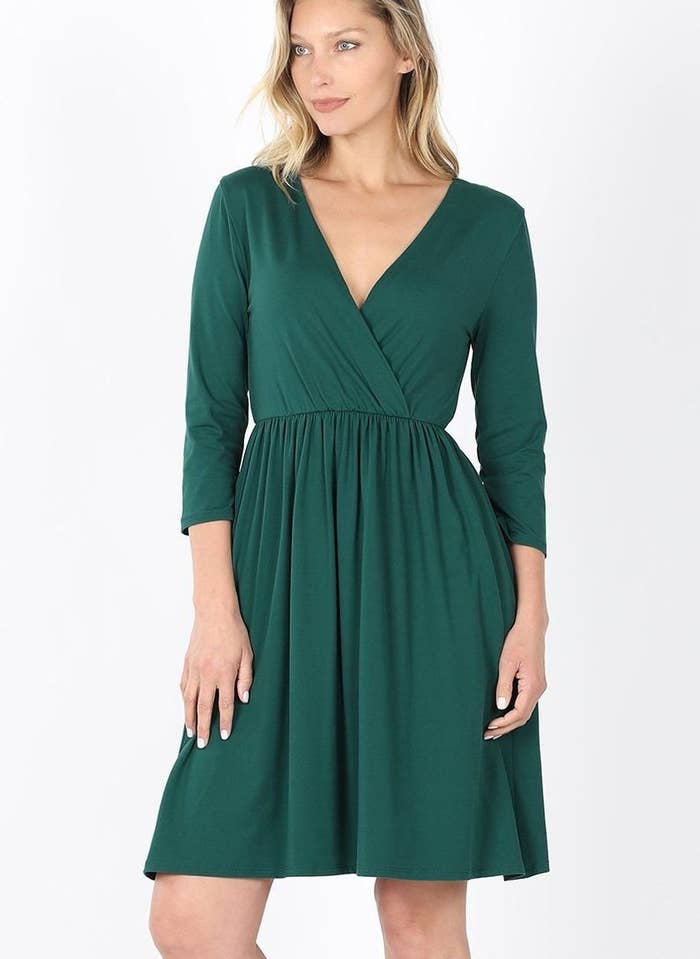 a model wearing the dress in green with a surplice neckline