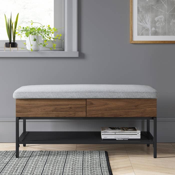 wooden bench with grey cushion against a wall