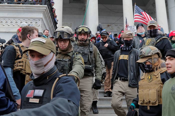 Men wearing camouflage military-style gear and outfits crowd a staircase