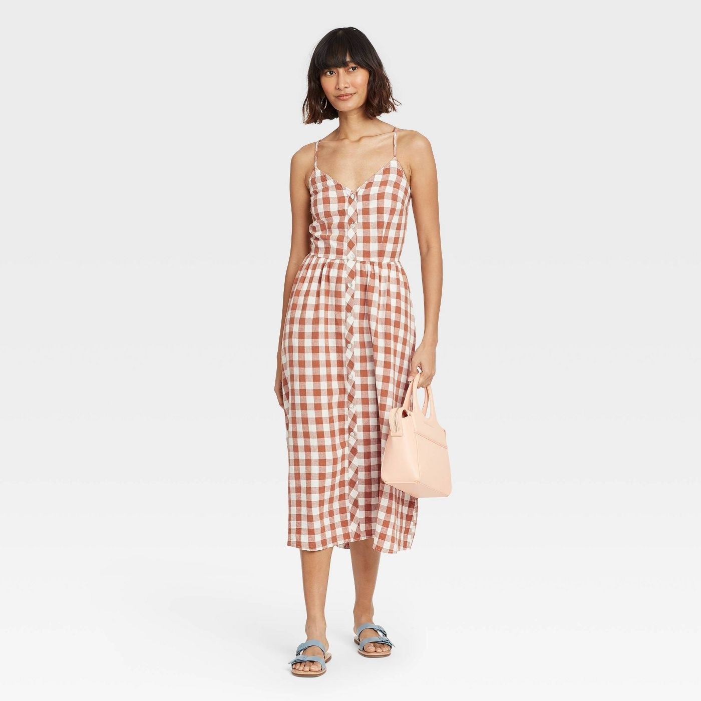 Model wearing midi dress with burnt orange and white checkers