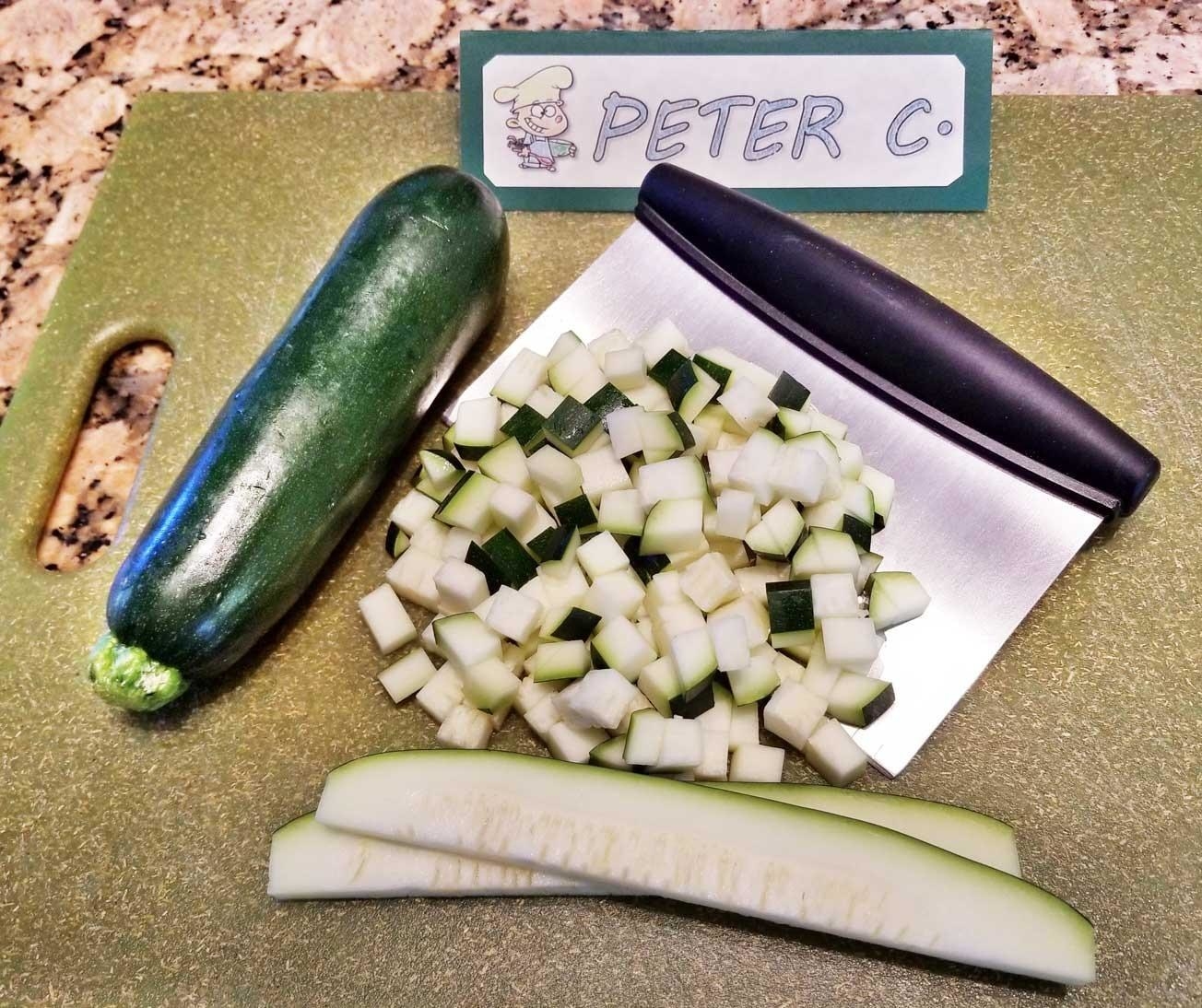 A chopper on a cutting board with diced zucchini