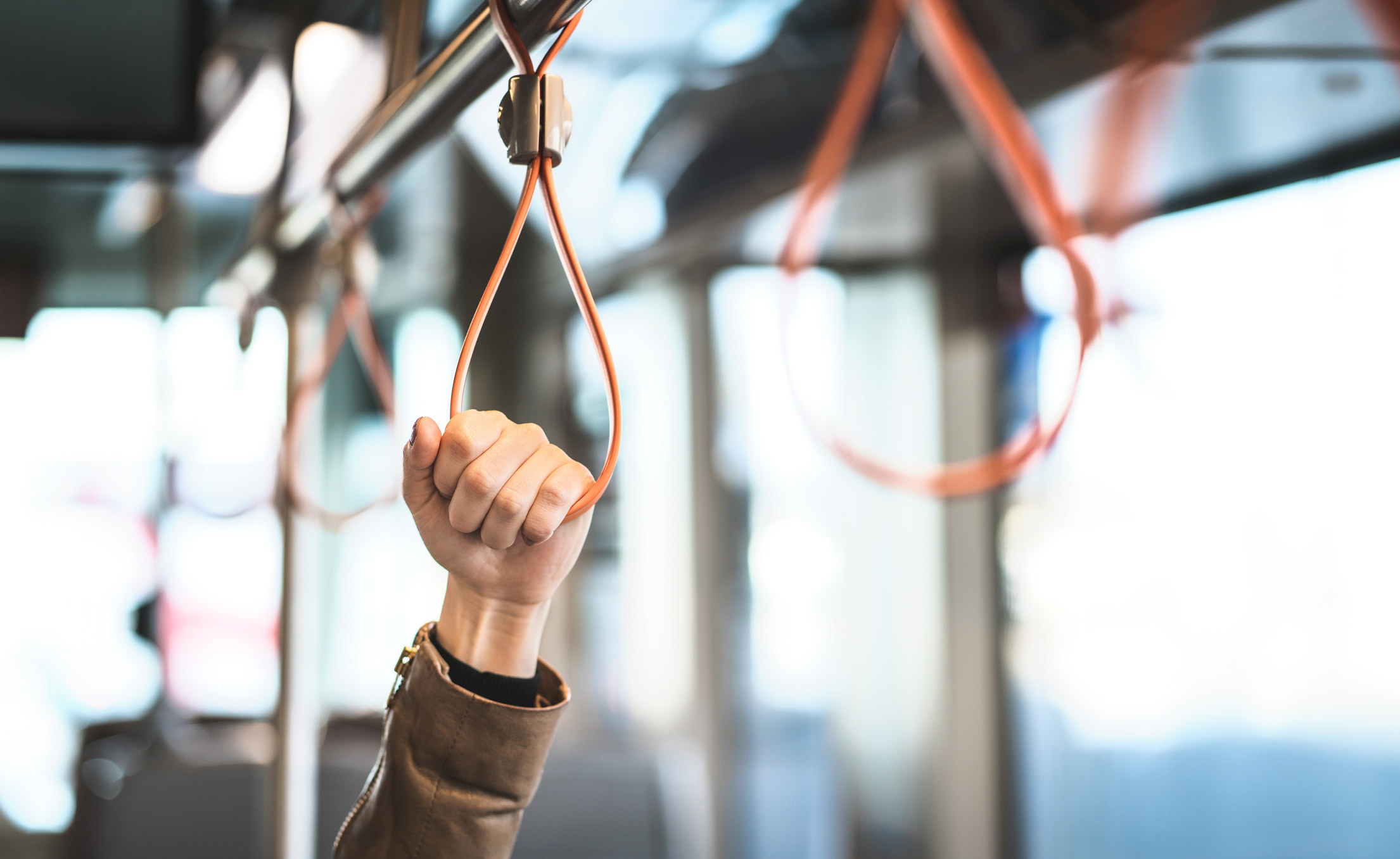 A hand holding on to a safety loop on the train