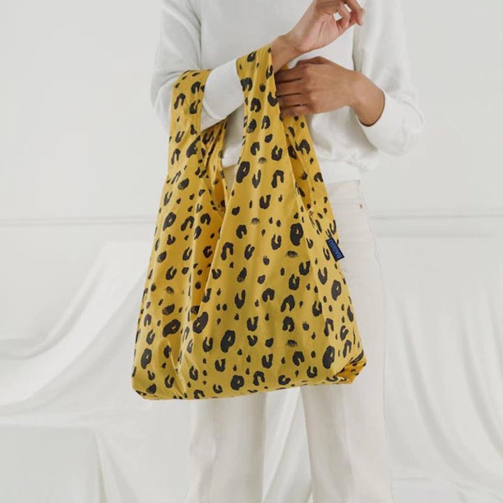 A person holding a large shopping bag from their arm